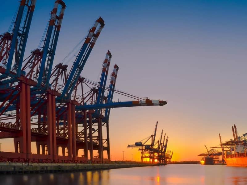 A ship docked in a port at sunset.