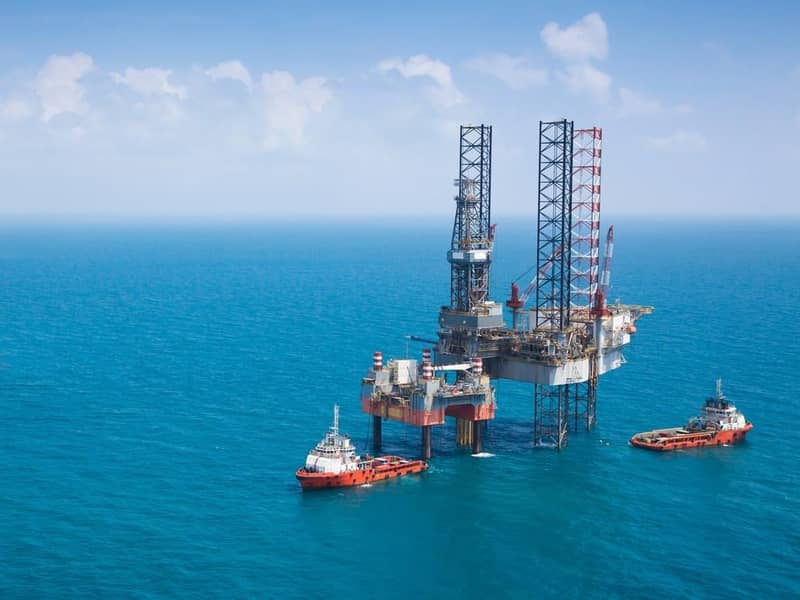 Two oil rigs and vessels in the middle of the ocean.