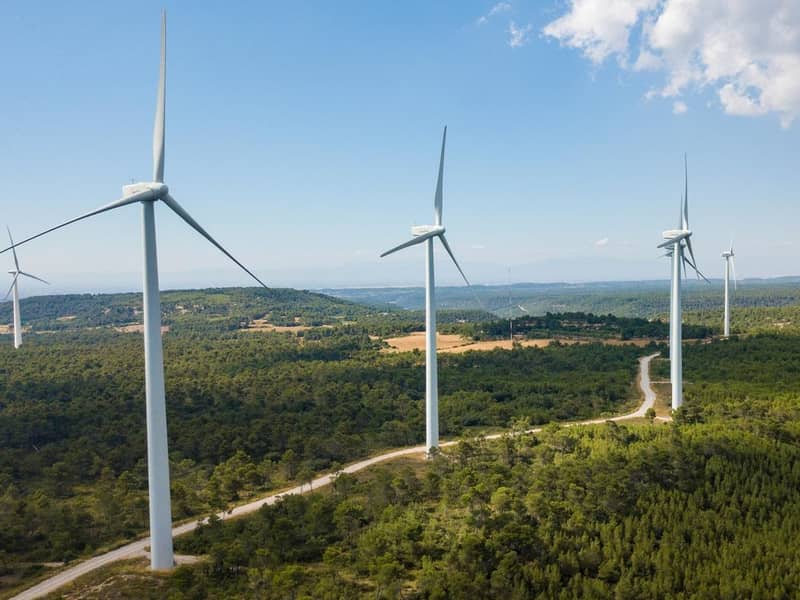 Wind turbines placed along a winding country road.