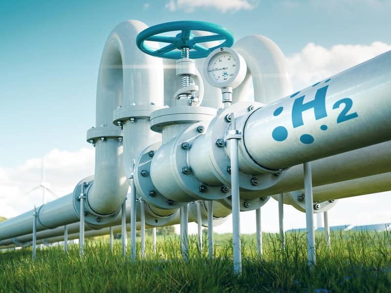 3D render of hydrogen pipelines in a field with wind turbines in the distance.