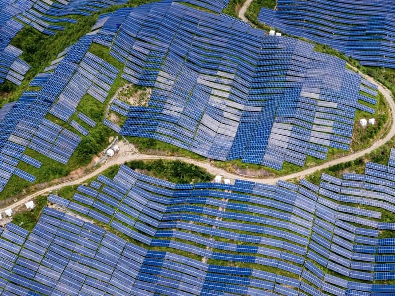 An aerial view of a countryside/hilltop solar farm.