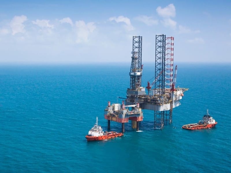 Two oil rigs and vessels in the middle of the ocean.