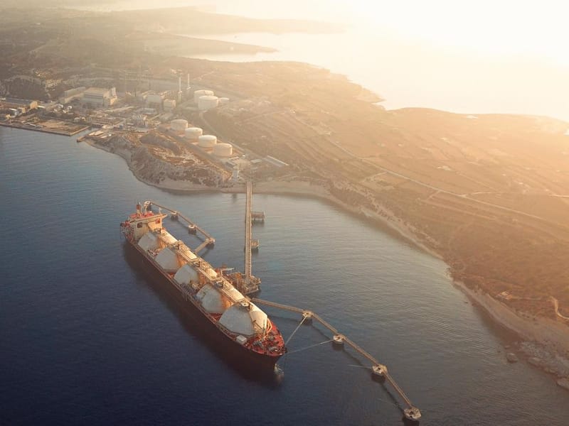 High angle view of a Gas Tanker moored to the jetty close to a power station during a foggy sunrise.
