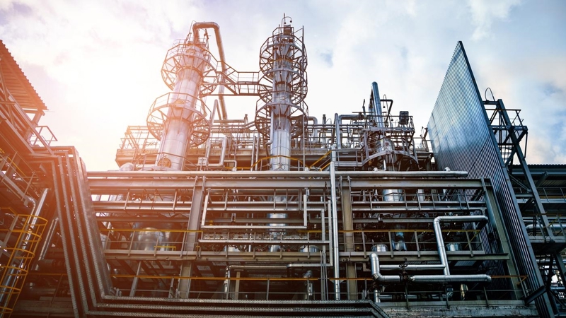 The exterior of an industrial plant with several levels and multiple criss-crossing pipes, tubes and platforms.