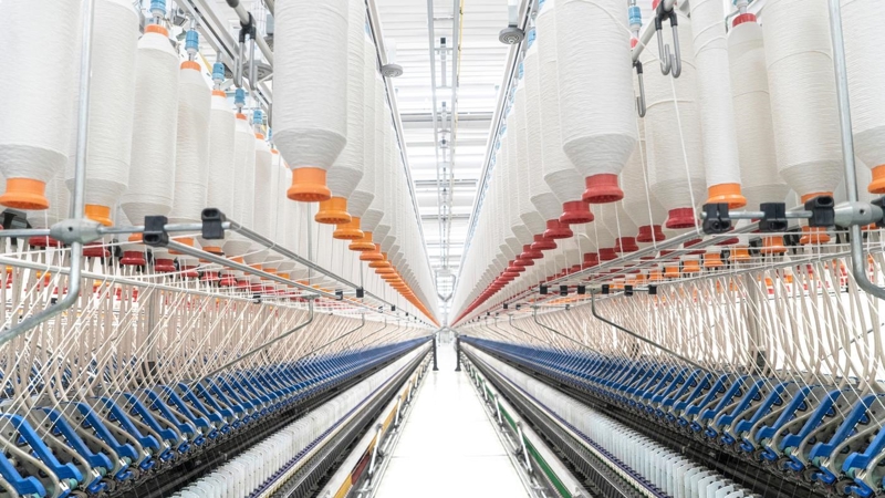 The interior of a factory with hundreds of raised spindles, weaving fibres from the machinery below.
