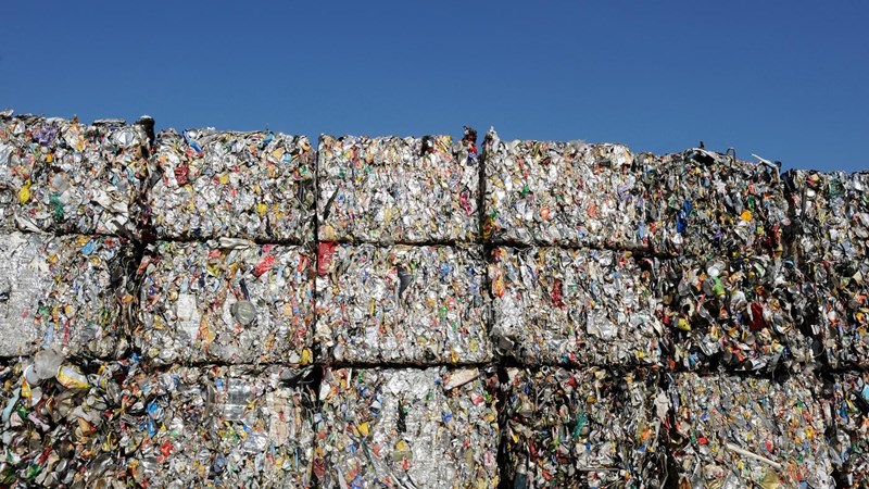 Multiple bales of plastic waste, piled high with a blue sky in the background.