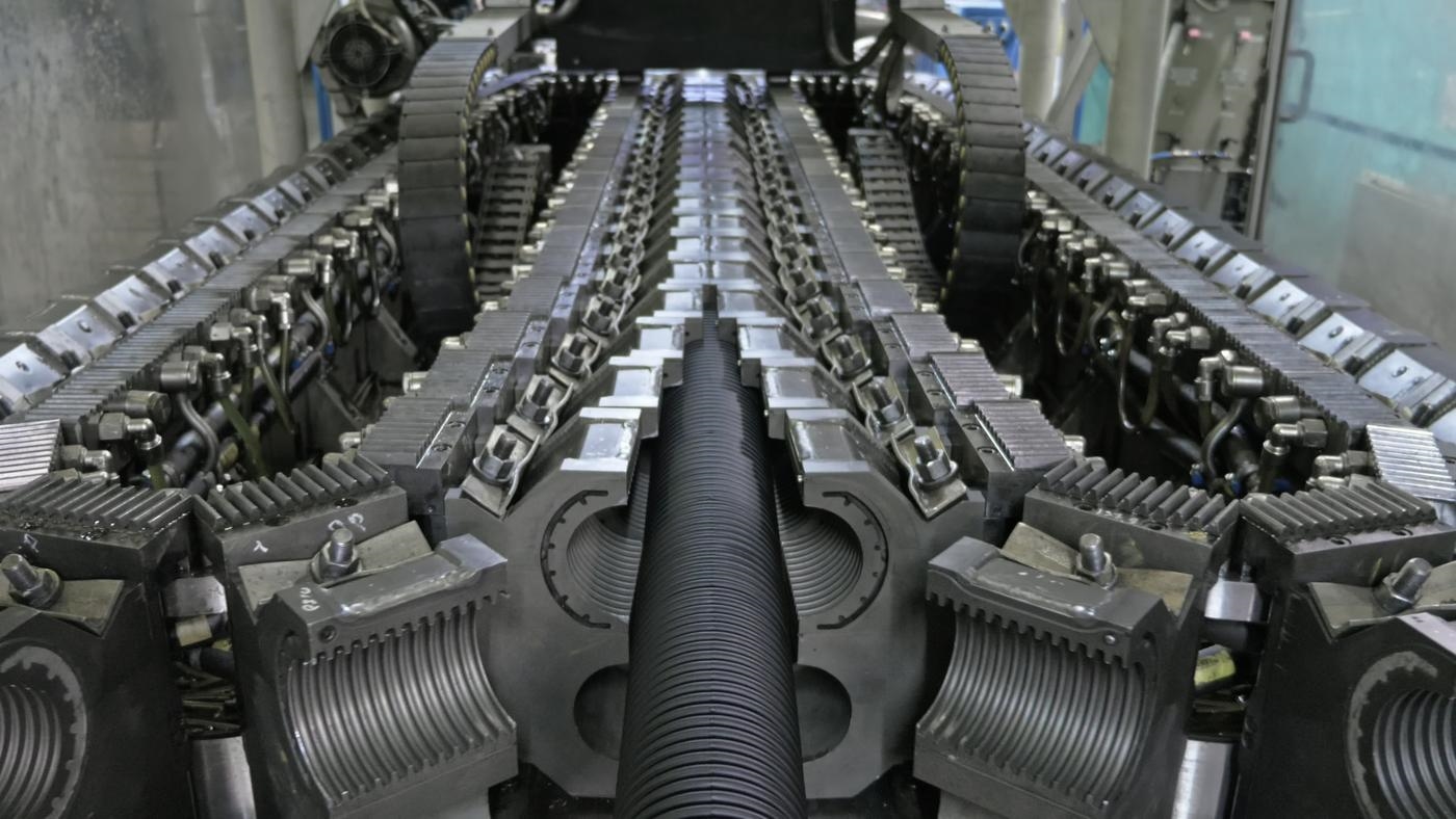 A close-up of a large mechanical conveyor belt, inside a factory.