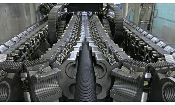 A close-up of a large mechanical conveyor belt, inside a factory.