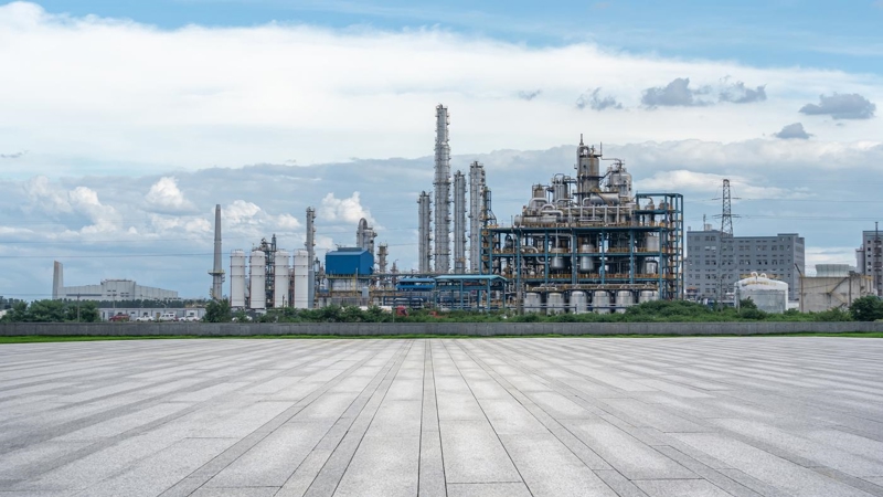 An oil refinery with electricity pylons and a cloudy sky in the background.