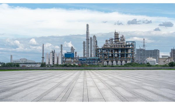 An oil refinery with electricity pylons and a cloudy sky in the background.