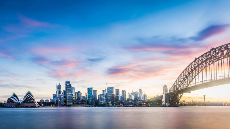 Panorama of Sydney skyline at sunset. Colourful clouds are over the city, the Harbour Bridge and Opera House.