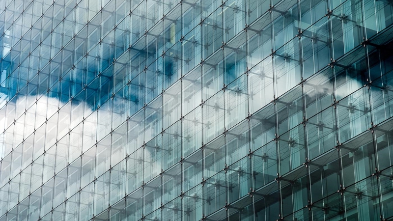 Blue clouded sky reflected in glass frontage of a modern glass building.