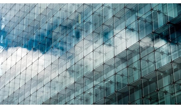 Blue clouded sky reflected in glass frontage of a modern glass building.