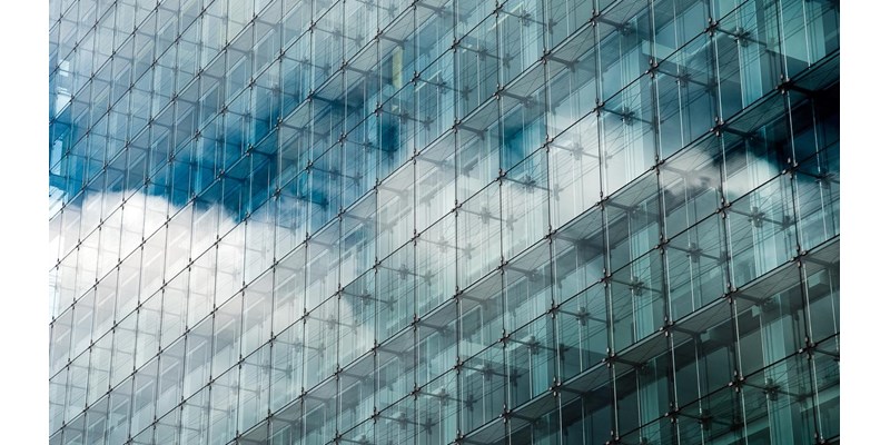 Blue clouded sky reflected in glass frontage of a modern glass building.
