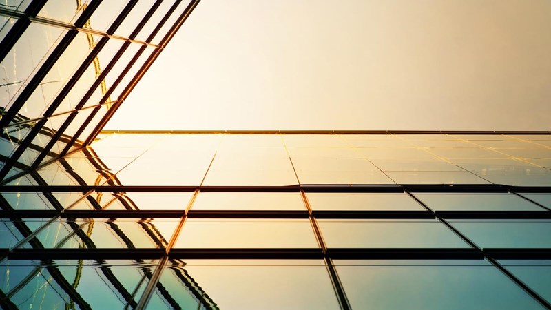 Modern angled corporate building, the sunlight reflecting against the glass.