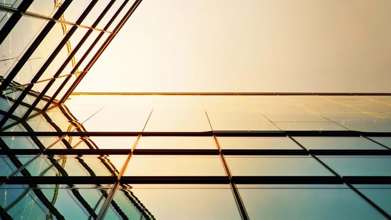 Modern angled corporate building, the sunlight reflecting against the glass.