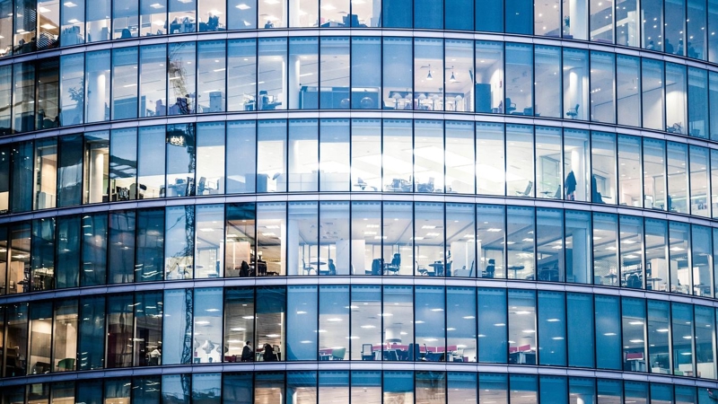 A curved glass office building, with interiors visible.  London, UK.