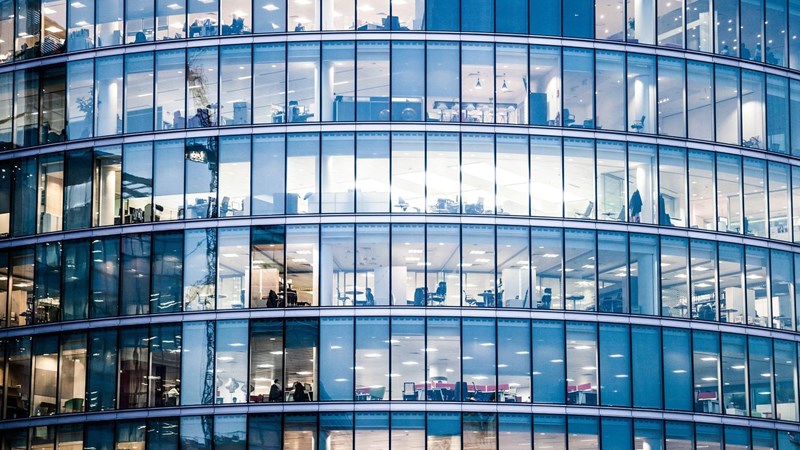 A curved glass office building, with interiors visible.  London, UK.