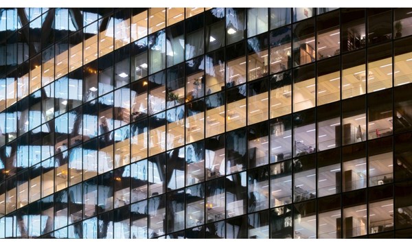 Reflection of illuminated office building in glass office facade in Paris, France.