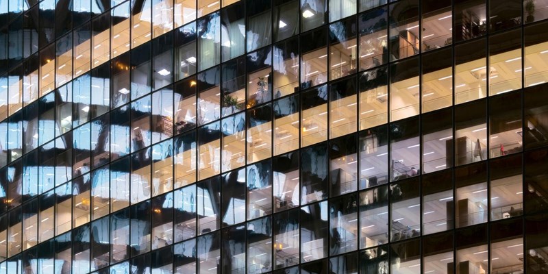 Reflection of Illuminated office building in glass office facade in Paris, France.