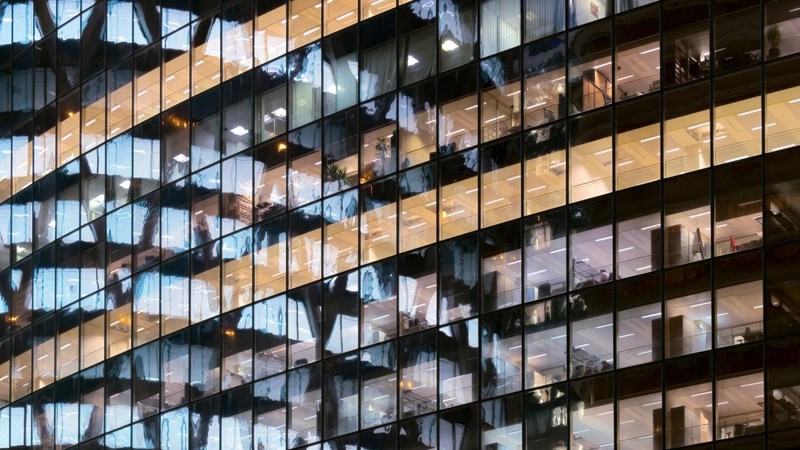 Reflection of illuminated office building in glass office facade in Paris, France.