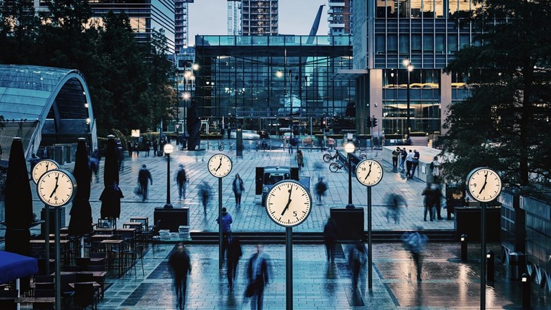 Blurred People walking and clocks in front of Canada Square, Canary Wharf, London.