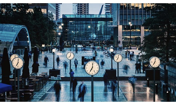 Blurred People walking and clocks in front of Canada Square, Canary Wharf, London.