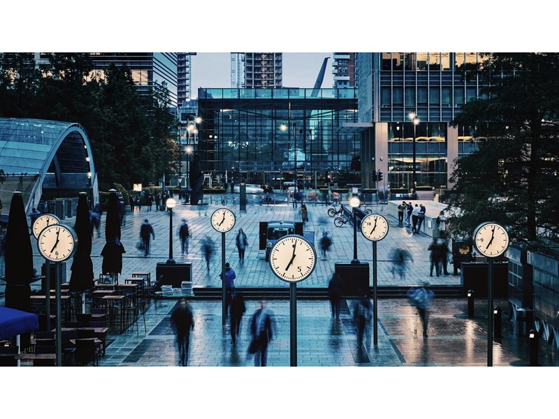 Blurred People walking and clocks in front of Canada Square, Canary Wharf, London.