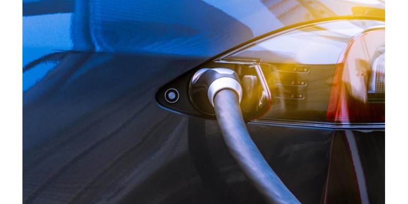 Electric vehicle charging cable plugged into the side of a black car.
