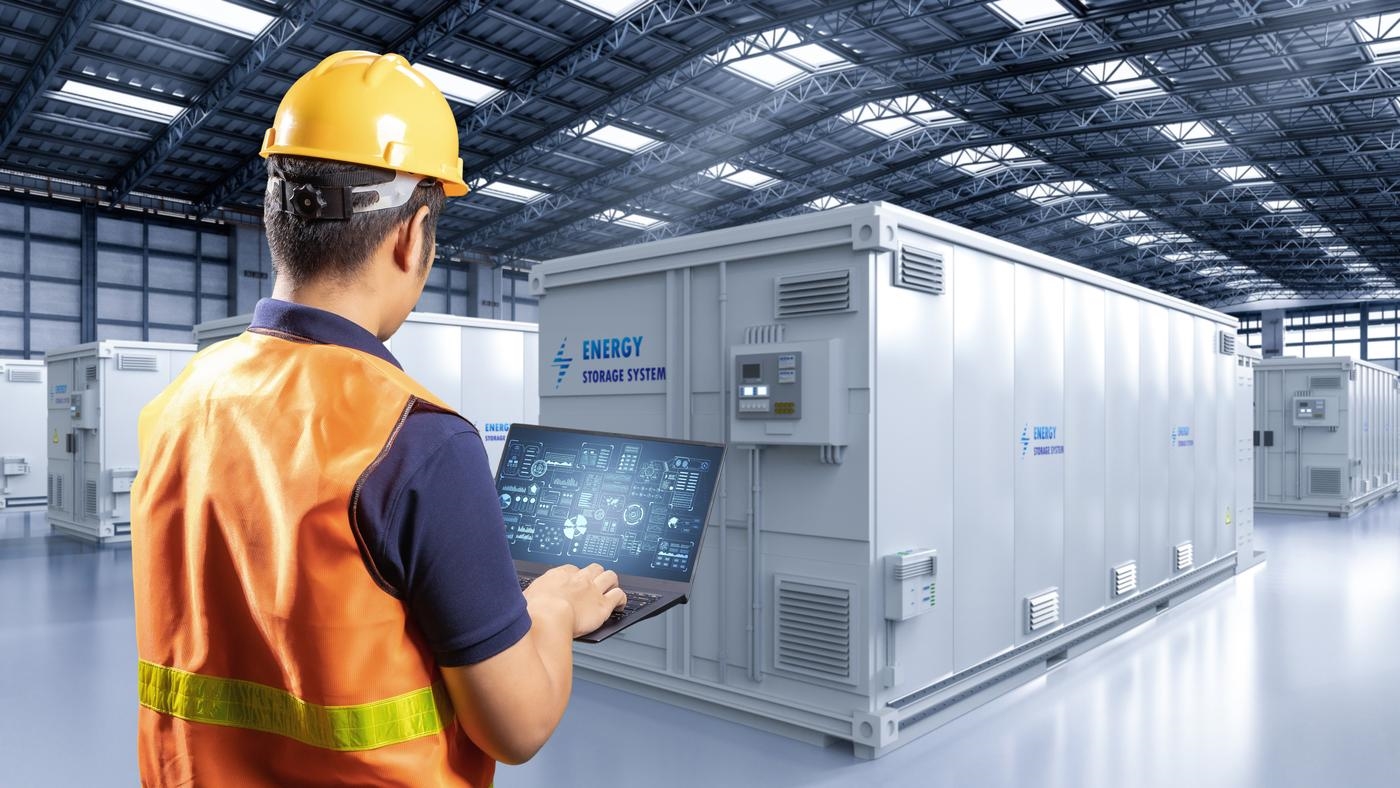 Engineer controlling energy storage system or battery container unit in factory.