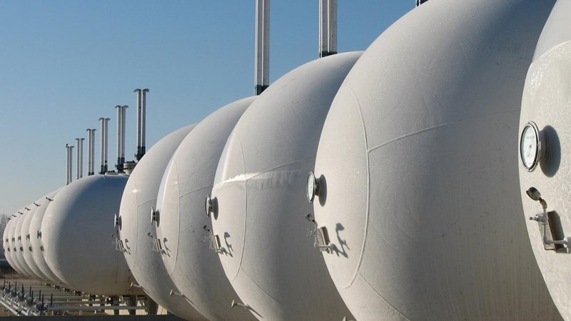 A row of white gas cylinders lined up in a field.