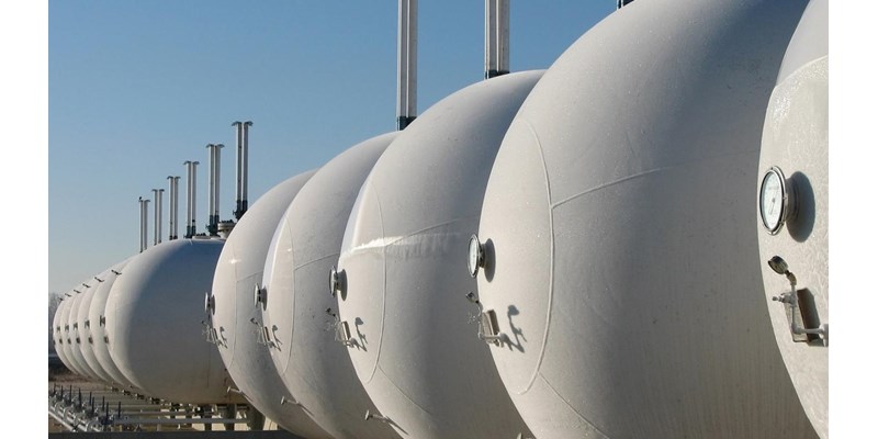 A row of white gas cylinders lined up in a field.