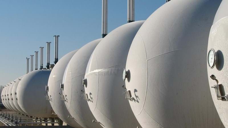 A row of white gas cylinders lined up in a field.