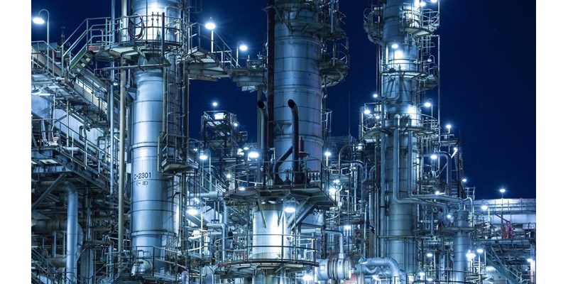 An illuminated gas/oil refinery at night.