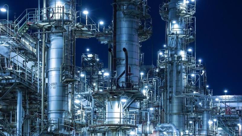 An illuminated gas/oil refinery at night.