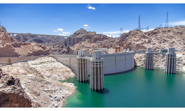 The hoover dam in Nevada, a bridge and electricity pylons on the surrounding rocky hills.