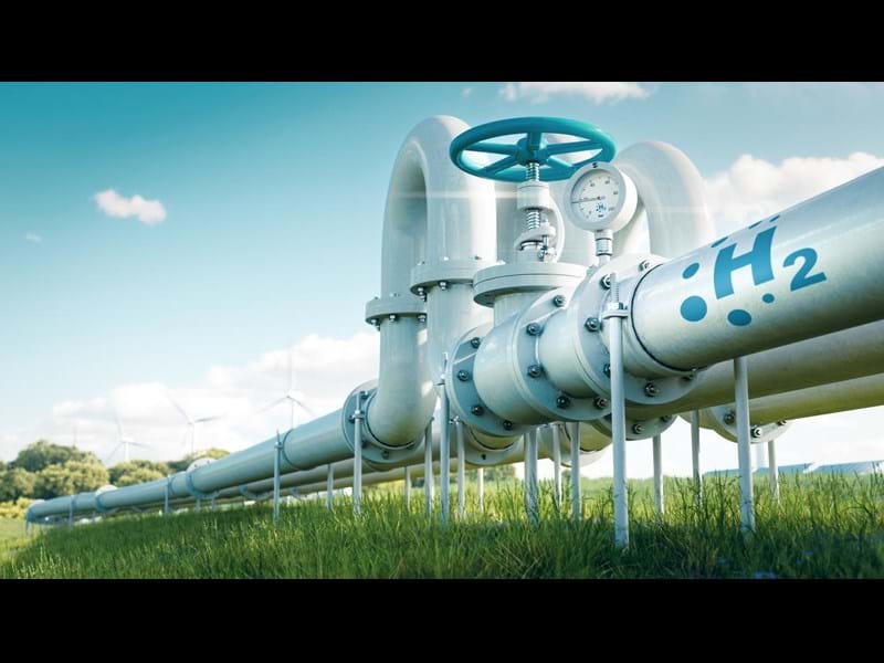 3D render of hydrogen pipelines in a field with wind turbines in the distance.