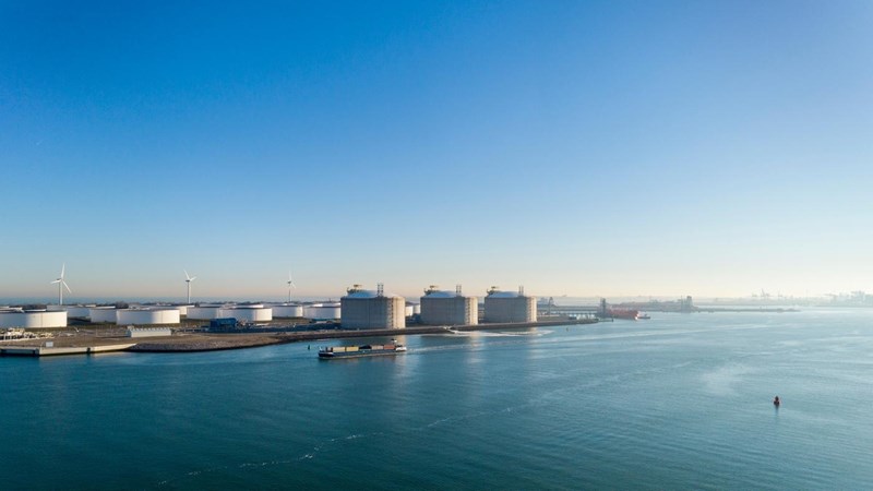 LNG tanks and wind turbines at the banks of a river.