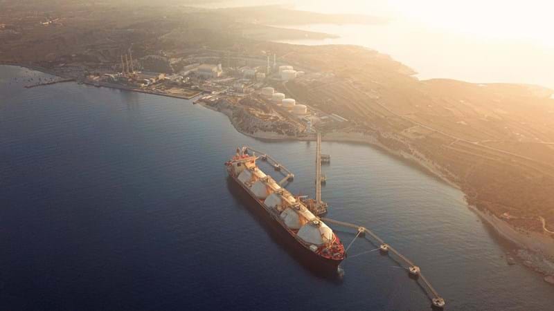 High angle view of a Gas Tanker moored to the jetty close to a power station during a foggy sunrise.