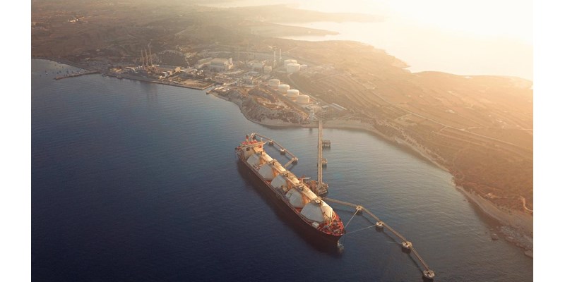 High angle view of a Gas Tanker moored to the jetty close to a power station during a foggy sunrise.