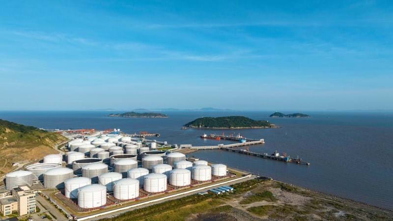Drone Aerial view Oil ship tanker load or unload oil at loading dock from Large Tank warehouse with Terminal commercial port and cityscape background for transportation on the sea.