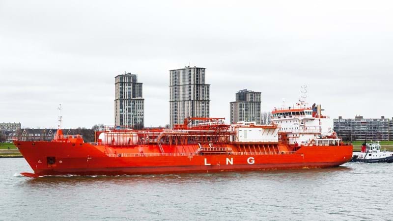 A gas carrier goes along the canal, accompanied by a tug in the city of Rotterdam, the Netherlands.