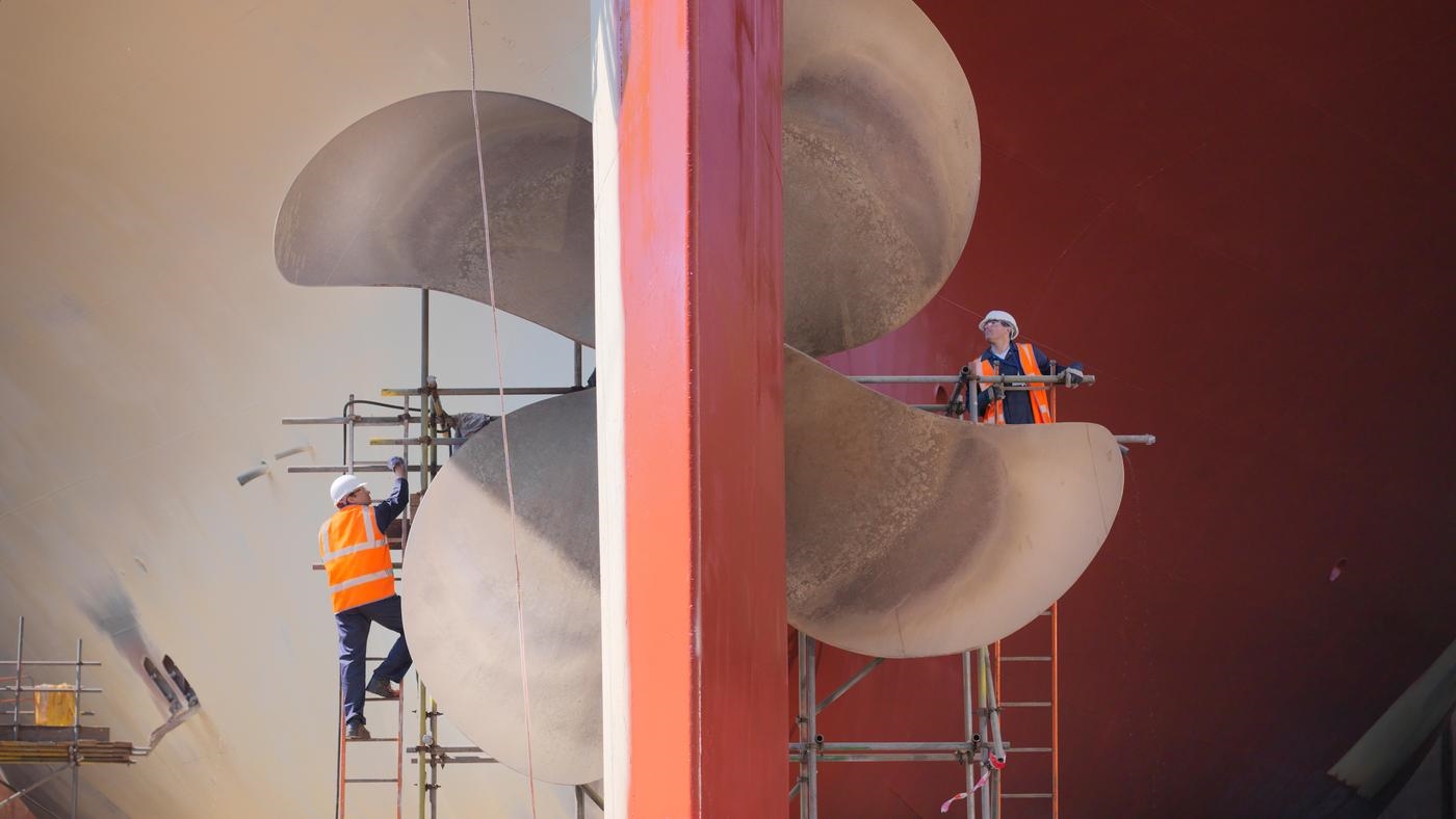 Two engineers checking a ships propeller in a dry dock.
