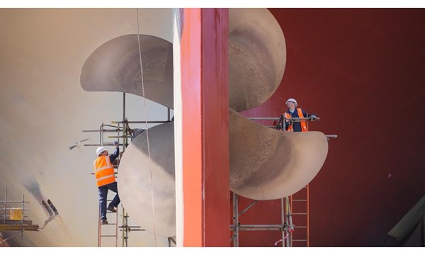 Two engineers checking a ships propeller in a dry dock.