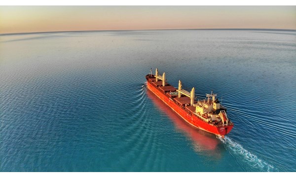 Lone empty container ship in an open expanse of water.