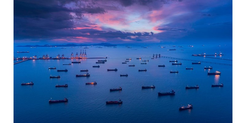 Aerial view Oil ship tanker park on the sea at dusk with beautiful sky waiting for load/unload oil from refinery for transportation.