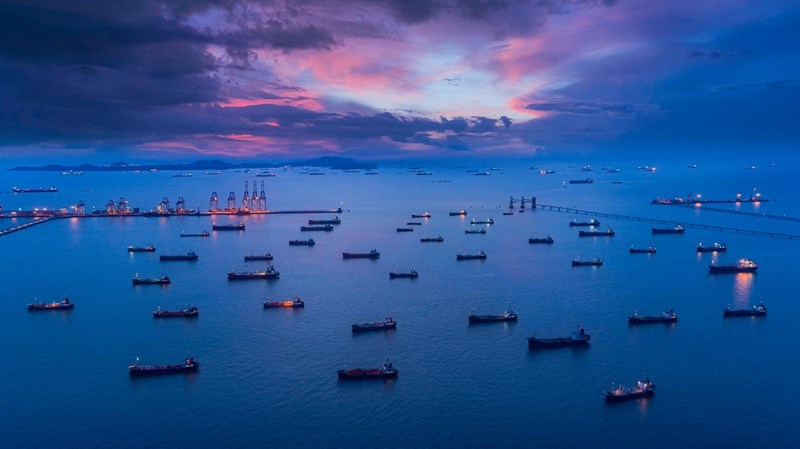 Aerial view Oil ship tanker park on the sea at dusk with beautiful sky waiting for load/unload oil from refinery for transportation.