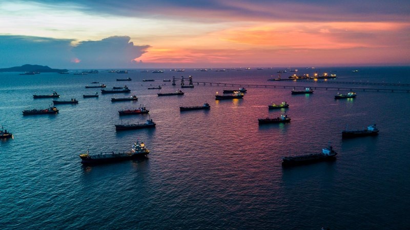 Aerial view Crude oil tanker under cargo operations on typical shore station with clearly visible mechanical loading arms and pipeline infrastructure.