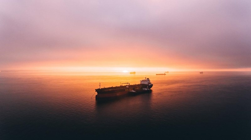 Several container ships on an open expanse of water at dusk.