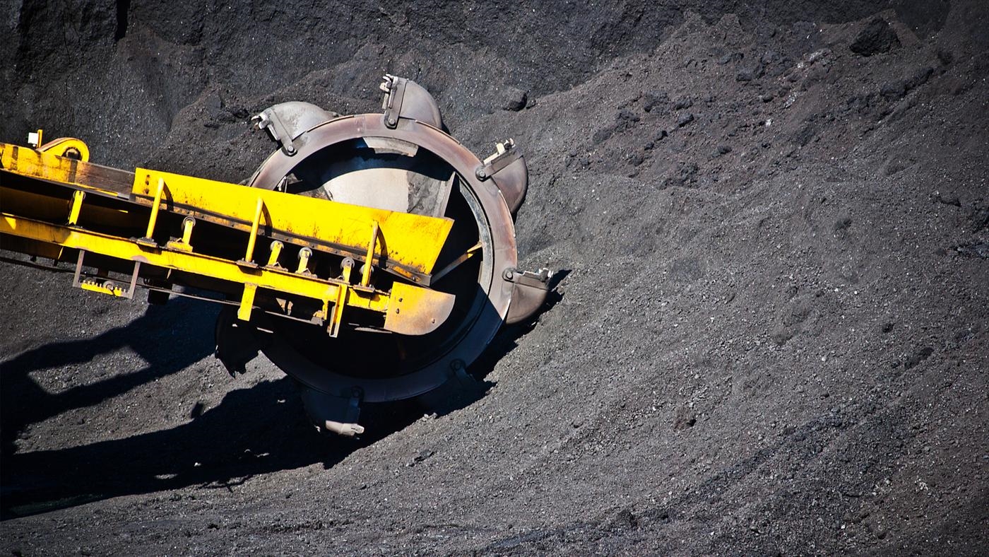 A bulldozer digging into a pile of coal.